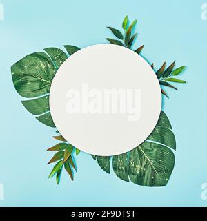 Composition of summer flowers. Round blank paper, green palms on a pastel blue background. Flat lay, top view, copy space, square Stock Photo
