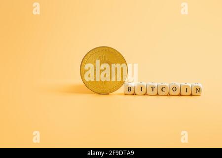 Bitcoin in a minimalist concept on a yellow background with the inscription Bitcoin Stock Photo