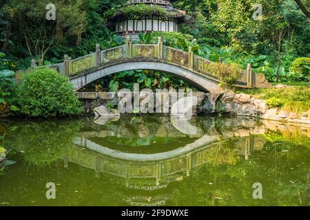 Shenzhen, China. October, 2019. Reflection of the stone bridge in Shenzhen International Garden and Flower Expo Park. The park serves multiple functio Stock Photo