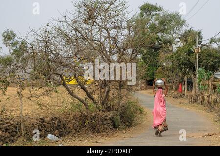 Mandu, India - March 2021: A woman carrying a bucket of water on her head on March 15, 2021 in Mandu, Madhya Pradesh, India. Stock Photo