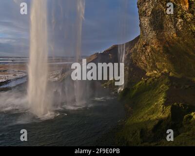 Stunning view of majestic cascade Seljalandsfoss, located on the southern coast of Iceland near ring road, from behind the waterfall in the evening. Stock Photo