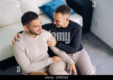 Gay couple sitting near the couch at home in a romantic moment Stock Photo