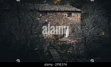 A side view of an abandoned old semi-destroyed building in the deep dark forest Stock Photo