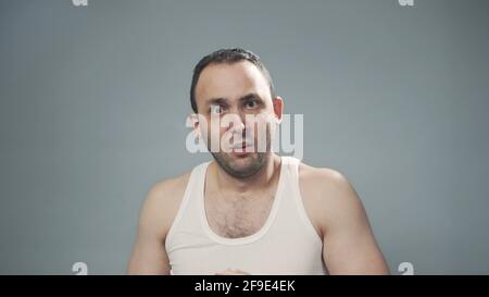 Photo of young bristly scared man on grey Stock Photo