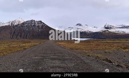 Rough landscape with diminishing perspective of gravel road leading to Svínafellsjökull glacier in the Öræfajökull mountain range in south Iceland. Stock Photo