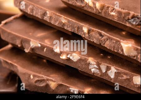 Close up of Belgian milk chocolate. Stack of milk and dark chocolate with nuts. Heap of chocolate bars. side view. Bitter chocolate on blurredbackgrou Stock Photo