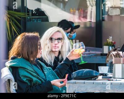 Constanta, Romania - 02.25.2021: Two women enjoying a nice day at a outdoor terrasse or cafe restaurant in Tomis Turistic Port Stock Photo