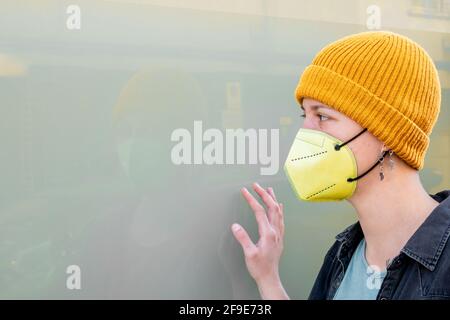 A portrait of a woman wearing a yellow beanie with a facemask in Spain - COVID-19 Stock Photo