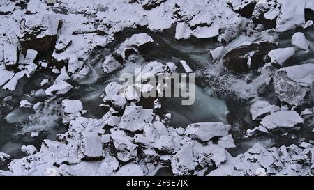 High angle view of bizarre landscape with river bed of partly frozen mountain stream Stórilækur surrounded by rocks near Hundafoss, Iceland. Stock Photo