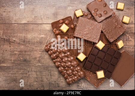 Composition bars and pieces of different milk and dark chocolate, on wooden table. Top view of pieces of chocolate bar on rustic wood background. clos Stock Photo