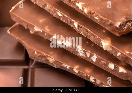 close up of chocolate pieces stack. Top view of chocolate bar with hazelnuts. Stacked chocolate bars on macro photo. Stock Photo