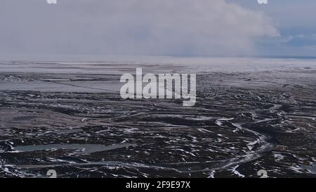 Aerial panoramic view of the sparse landscape of Öræfasveit (Icelandic for wasteland, also Öræfi) with white and black pattern of snow and rocks. Stock Photo