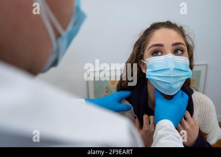 Unrecognizable medic in gloves examining lymph nodes of female patient during appointment in modern hospital Stock Photo