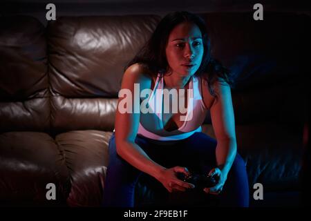Concentrated gamer using joy pad and playing video game in dark room Stock Photo