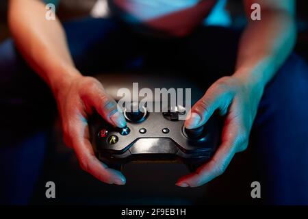 Crop unrecognizable gamer using joy pad and playing video game in dark room Stock Photo