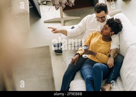 From above of tender multiracial couple lying on couch and spending time together at home Stock Photo