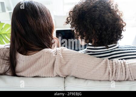 Back view Woman with netbook talking to boyfriend while looking at screen on couch in house room Stock Photo