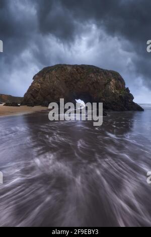Majestic view of rough rocky formations on wet Penarronda beach under cloudy sky in Asturias Stock Photo