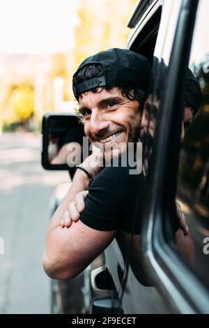 Side view of happy off-road vehicle driver leaning out of the window and looking at camera Stock Photo
