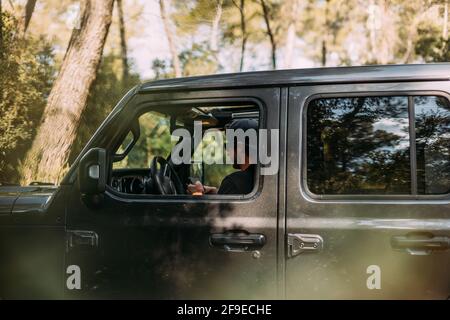 Side view of an adventurer using his smartphone inside his off-road car before starting the journey Stock Photo