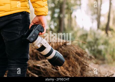 Rear view of an anonymous photographer holding his camera in the mountain with blur background Stock Photo