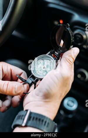 Anonymous adventurer holding a compass to orient himself inside his car Stock Photo