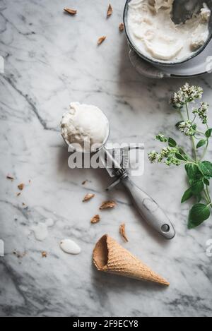 From above of waffle cone near meringue milk gelato scoops and fresh mint leaves on marble table Stock Photo