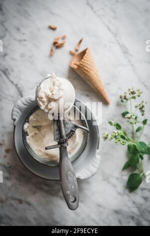 From above of waffle cone near meringue milk gelato scoops and fresh mint leaves on marble table Stock Photo