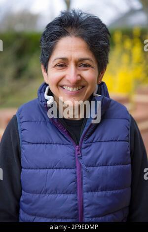Asian Indian middle aged menopausal woman outdoors looking happy in England, UK Stock Photo