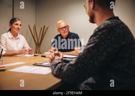 Two business people taking job interview of a man in office boardroom. business partners interviewing new candidate in office. Stock Photo