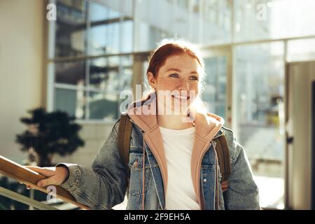 Female student standing in college and looking away. Happy young woman standing in college. Stock Photo