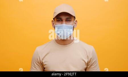 Portrait of young indian man with face medical mask isolated on yellow background. High quality photo Stock Photo