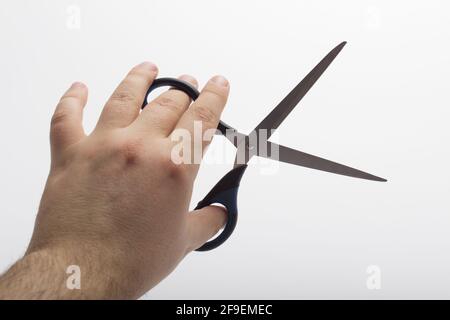 Hand is holding a scissors isolated on a white background. Stationery scissors in hand isolated on a white background. Stock Photo