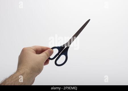 Hand is holding a scissors isolated on a white background. Stationery scissors in hand isolated on a white background. Stock Photo