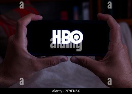 Spain. 04, 18, 2021. Close-up of a man holding a smartphone with the HBO home screen on his sofa at night Stock Photo