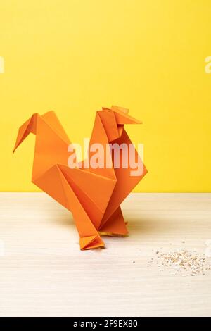 A vertical shot of an orange origami chicken on a wooden surface Stock Photo