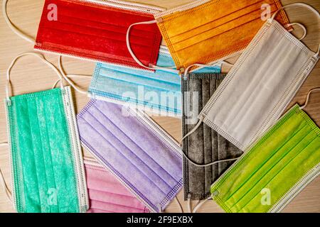 A top view of face masks of different colors on a textured table Stock Photo