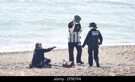 Brighton UK 18th April 2021 - Police and PCSO's clear a section of Brighton beach today after it is believed a metal detectorist found a suspect item on the shingle, possibly a WW2 mortar shell near the pier : Credit Simon Dack / Alamy Live News Stock Photo