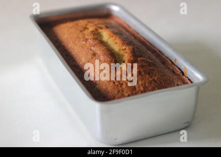 Home baked vanilla cake inside the loaf tin tray. Shot on white background. Stock Photo