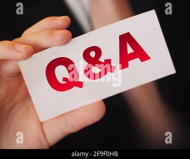 Q and A Questions and Answers sign on business card shown by a businessman,. Business concept. Stock Photo