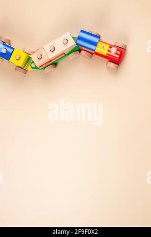 Wooden toy train with multi colored blocks on pastel beige background. Top view Stock Photo