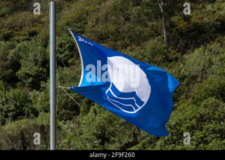San Pedro de la Ribera, Spain - August 16, 2020: Blue flag of FEE, European Foundation for Environmental Education, fluttering in the wind on a beach Stock Photo