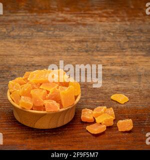 dried mango fruit diced - small wooden bowl on a weathered wood background Stock Photo