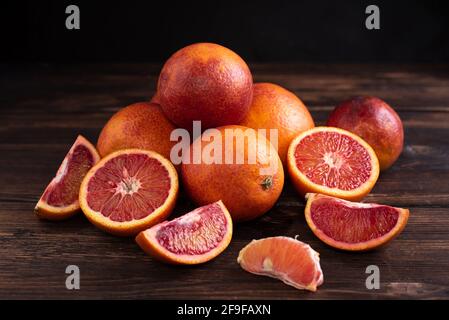 Hill of juicy fresh blood orange on a dark wooden background, healthy food, rustic style, close up. Stock Photo