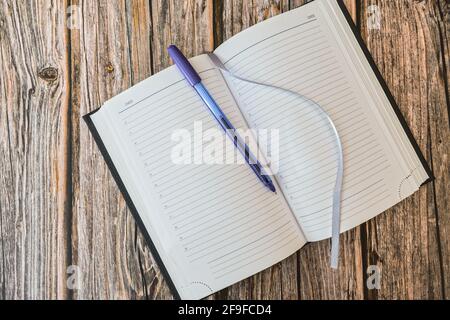 Opened diary or notebook for notes with pen on wooden table top view Stock Photo