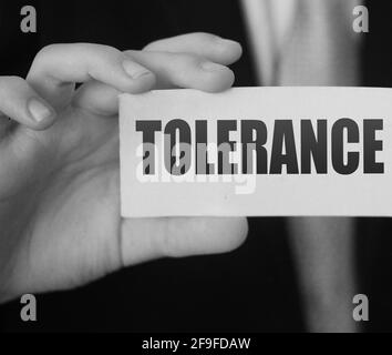 Tolerance words on a card in businessman hand. Social concept against discrimination at workplace. Stock Photo