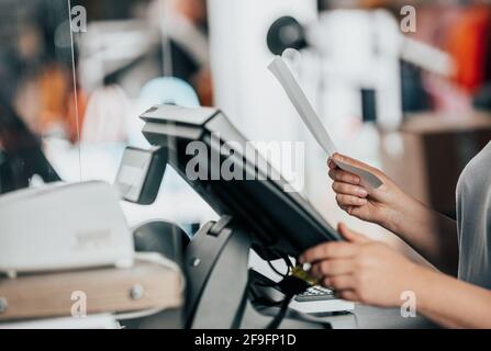Young woman doing process payment with the bill or invoice on the POS cash terminal in the shop, finance concept Stock Photo