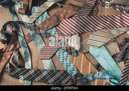 Messy pile of colored and patterned ties on wooden background from top view Stock Photo