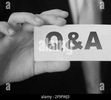 Q and A Questions and Answers sign on business card shown by a businessman,. Business concept. Stock Photo
