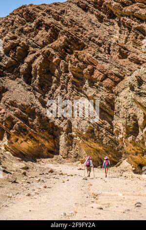 Two Female Hikers Hike Through Golden Canyon In Death Valley National Park Stock Photo